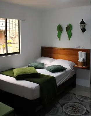 a bedroom with a large bed with green pillows at Donde María Yarce Casa Turística in Jardin