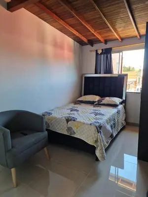 a bedroom with a bed and a chair and a window at GIGANTE y ELEGANTE APARTAMENTO UNIFAMILIAR in Belén