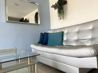 a living room with a white couch and a mirror at Central Family Home with Air Conditioning in Sabaneta