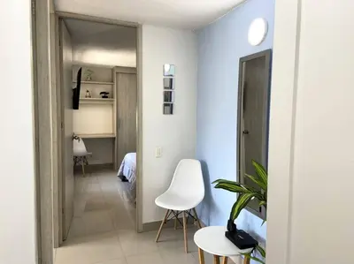 a room with a hallway with a white chair and a table at Central Family Home with Air Conditioning in Sabaneta