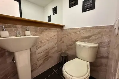 a bathroom with a white toilet and a sink at Charm of Las Palmas in El Salvador