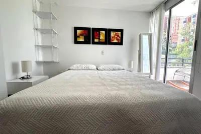 a white bedroom with a large bed with three pictures on the wall at Charm of Las Palmas in El Salvador