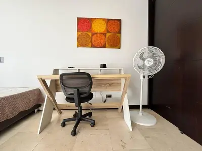 a desk with a chair and a fan in a room at Magical Laureles in Medellín