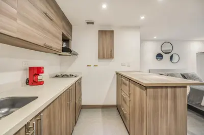 a kitchen with wooden cabinets and a red appliance at Aparta Estudio en Edificio La Frontera in Medellín