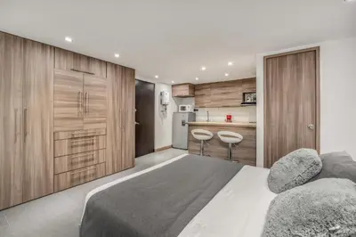 a bedroom with a large bed and a kitchen at Aparta Estudio en Edificio La Frontera in Medellín