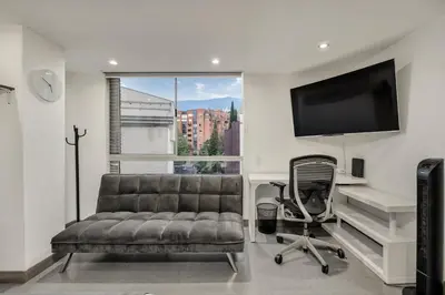 a living room with a couch and a chair and a television at Aparta Estudio en Edificio La Frontera in Medellín