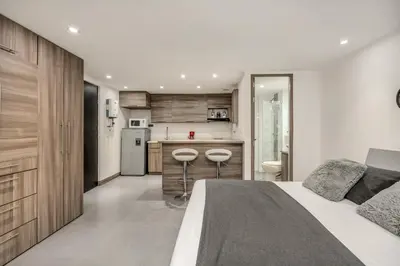 a bedroom with a large bed and a kitchen at Aparta Estudio en Edificio La Frontera in Medellín