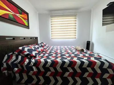 a bedroom with a bed with a colorful comforter at Serene Laureles in América