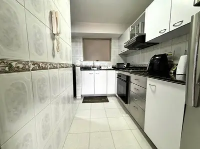 a kitchen with white cabinets and a white tile floor at Serene Laureles in América