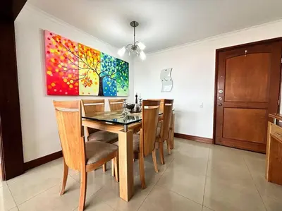 a dining room with a table and chairs and a painting at Serene Laureles in América