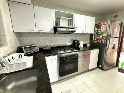 a kitchen with white cabinets and a stainless steel refrigerator at Serene Laureles in América