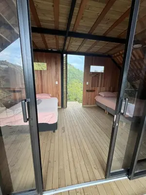 a room with two beds and a glass door at Tambo 3 Carriquí - Reserva Natural Salto del Buey in Montebello