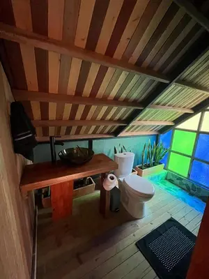 a bathroom with a toilet and a wooden ceiling at Tambo 3 Carriquí - Reserva Natural Salto del Buey in Montebello