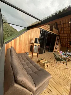 a couch sitting on a deck with a table and chairs at Tambo 3 Carriquí - Reserva Natural Salto del Buey in Montebello