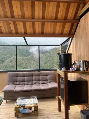 a living room with a couch and a large window at Tambo 3 Carriquí - Reserva Natural Salto del Buey in Montebello