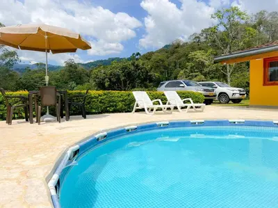 a swimming pool with a table and an umbrella at 15 mins to Jardín Spacious & Convenient House in Los Andes