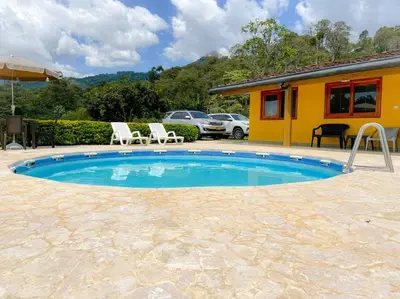 a swimming pool with two chairs and a house at 15 mins to Jardín Spacious & Convenient House in Los Andes