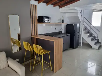 a kitchen with a counter and two yellow chairs at 302 Apartamento Completo en Medellín in Medellín