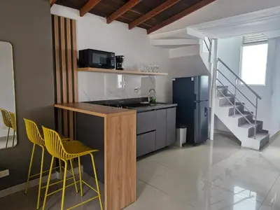 a kitchen with yellow chairs and a counter with a refrigerator at 302 Apartamento Completo en Medellín in Medellín