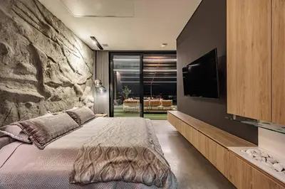 a bedroom with a large bed with a stone wall at Luxurious Farm House in Rionegro