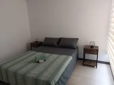 a bedroom with a bed with a green blanket at Oasis urbano, cerca a todo, a una cuadra del metro in Sabaneta