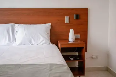 a bed with a wooden headboard and a table with a lamp at Crisalida Apartamento in Sabaneta