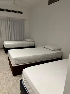 three beds in a room with white walls at Casa de la Cruz in Mariquita