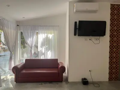 a living room with a couch and a television on a wall at Casa de la Cruz in Mariquita