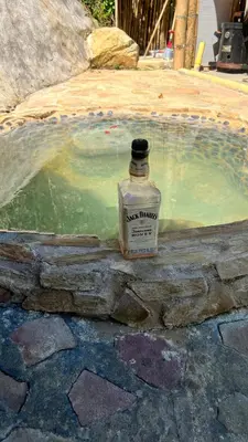 a bottle of whiskey sitting next to a small pool of water at Cabaña Glamping vista verde Cocorna in Cocorná