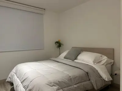 a bed in a bedroom with a white wall at Apartamento Exclusivo Manizales in Manizales