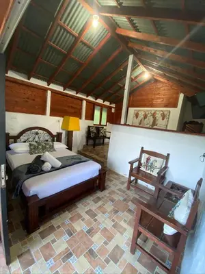 a bedroom with a bed and a chair in a room at Ecohotel La Italia- Hotel Venecia, Antioquia in Venecia