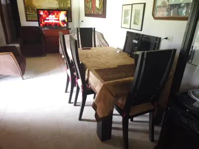 a dining room with a table with chairs and a television at Casa de campo barbosa Antioquia in Barbosa