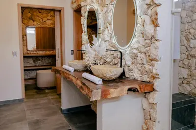 a bathroom with a stone wall and a mirror at La Gracia Hotel & Spa in San Jerónimo