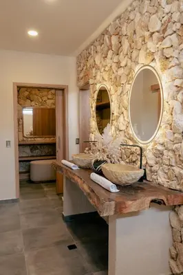 a bathroom with two sinks and a stone wall at La Gracia Hotel & Spa in San Jerónimo