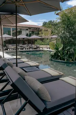 a row of chaise lounge chairs next to a swimming pool at La Gracia Hotel & Spa in San Jerónimo