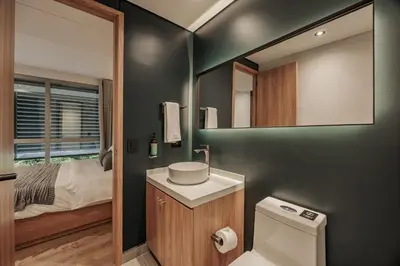 a bathroom with a toilet and a mirror and a bed at H10 - Provenza in Medellín