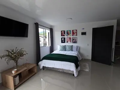 a bedroom with a bed and a flat screen tv at Hermoso Loft cerca al poblado y al metro in Medellín