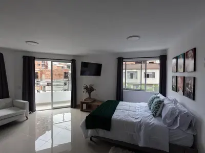 a bedroom with a bed and a couch and windows at Hermoso Loft cerca al poblado y al metro in Medellín