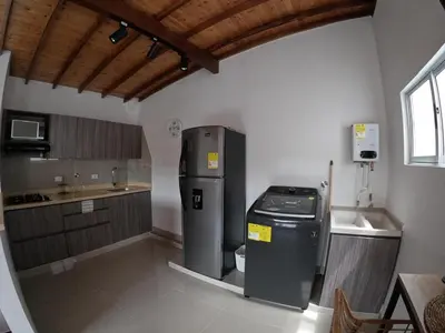 a kitchen with a refrigerator in the corner of a room at Hermoso Loft cerca al poblado y al metro in Medellín