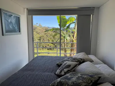 a bedroom with a bed and a large window at Mountain Home Close to Guatape Pueblo With Jacuzzi in Guatapé