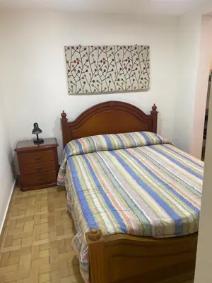 a bed with a striped comforter and a dresser in a bedroom at Acogedor loft, para 4 huéspedes Medellín Antioquia in Medellín