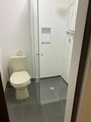 a bathroom with a toilet and a glass shower at Acogedor loft, para 4 huéspedes Medellín Antioquia in Medellín