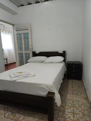 a bedroom with a large bed with white sheets at Hotel Quinchia in Quinchía