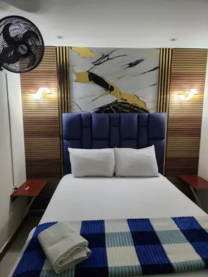 a bedroom with a large bed with a blue headboard at Hotel 50 Suites in Caldas