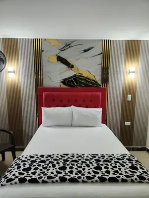 a bed with a red headboard with a painting above it at Hotel 50 Suites in Caldas