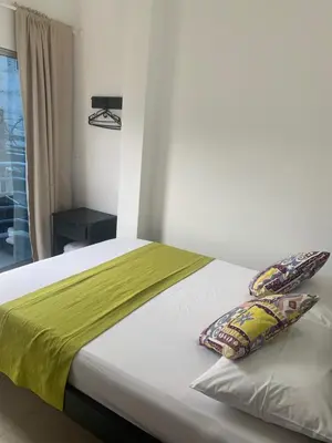 a bed with a green blanket and two pillows on it at Hotel Los Balcones in Doradal