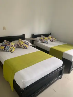 two beds with green and white sheets in a room at Hotel Los Balcones in Doradal