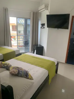 a room with two beds and a flat screen tv at Hotel Los Balcones in Doradal