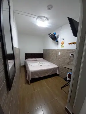 a small room with a bed and a mirror at Hospedaje Ricaribe in Medellín