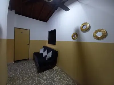 a waiting room with a black couch and two mirrors at Hospedaje Ricaribe in Medellín